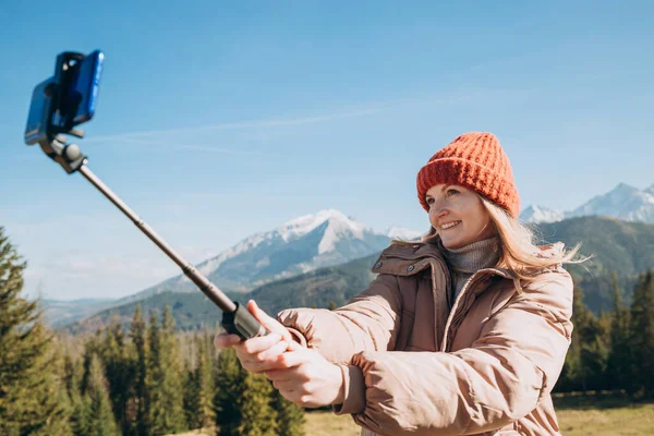 Mladá žena dělá selfie foto vysoko ve sněhových horách a užívá si výhled. Svoboda, štěstí, cestování a dovolená koncept, outdoorové aktivity — Stock fotografie