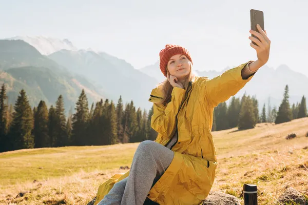 Młoda kobieta robi zdjęcie selfie wysoko w górach śniegu ciesząc się widokiem. Koncepcja wolności, szczęścia, podróży i wakacji, zajęcia na świeżym powietrzu — Zdjęcie stockowe