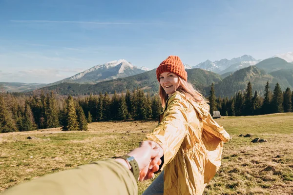 Caminante con sombrero rojo se encuentra en el borde del acantilado sobre el fondo y extiende una mano. Una mujer feliz le da una mano a alguien como yo. Vista en primera persona. — Foto de Stock