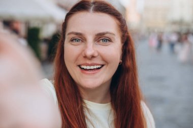 Güzel bir kadın eski binanın önünden geçerken selfie çekiyor. Kaygısız ve mutlu, güneşli yaz havası. Çevrimiçi iletişim kavramı