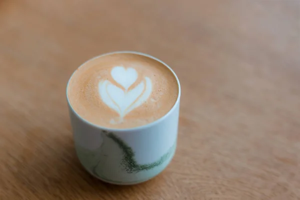 1杯のカプチーノとラテアート。カフェで茶色の木製のテーブルの上に白いカップでコーヒー。簡単な朝食の概念. — ストック写真