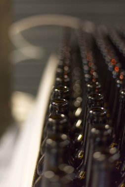 Glass products. Bottles for drinks. Industrial work, automated production of food and drinks. Details of local beer production line, Many bottles on conveyor belt in factory