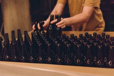 Glass products. Bottles for drinks. Industrial work, automated production of food and drinks. Details of local beer production line, Many bottles on conveyor belt in factory