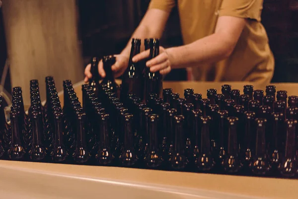 Glass products. Bottles for drinks. Industrial work, automated production of food and drinks. Details of local beer production line, Many bottles on conveyor belt in factory — Fotografia de Stock