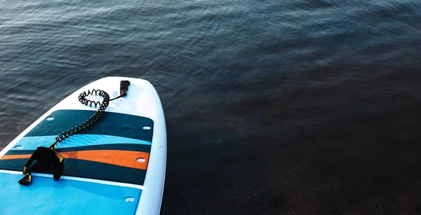 Surfbrett auf blauem Hintergrund mit sauberem Wasser. SUP-Boarding-Ausrüstung im Sonnenuntergang aus nächster Nähe. Wassersport im Freien. Verleih von Ausrüstung für das Schwimmen im Ozean oder Meer, Sommerzeit — Stockfoto