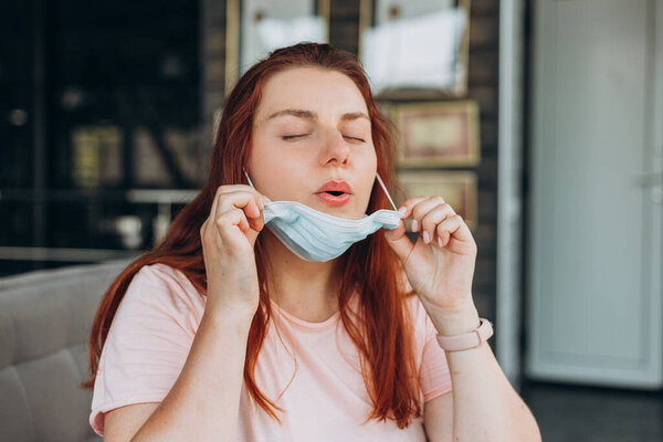 Счастливая женщина снимает защитную маску в помещении во время пандемии коронного вируса. Карантин и социальная дистанция. Девушка в ожидании рейса
