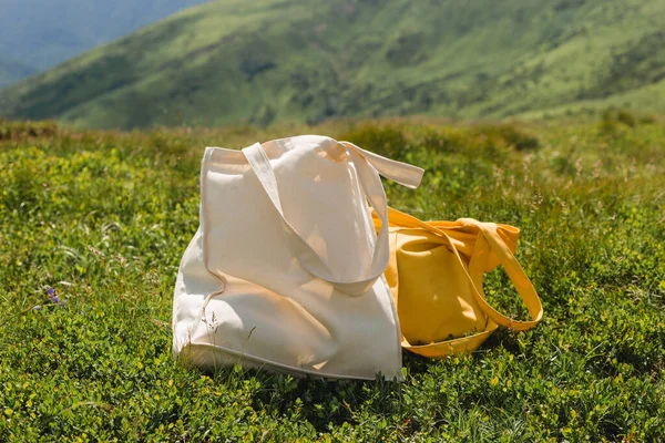 Canvas tote bags on green grass on the edge of the hill in the park. Eco Nature Friendly Style. Environmental Conservation Recycling Concept, mock-up