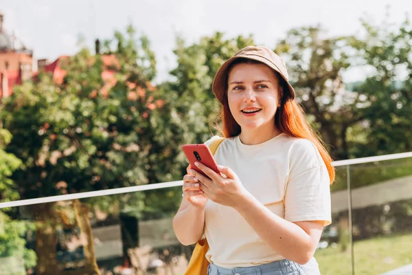 Portrét pozitivní veselá dívka použít chytrý telefon sdílet sociální média novinky oblečení styl stylový módní klobouk nad přírodou pozadí, letní čas — Stock fotografie