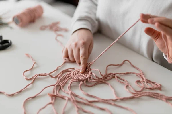 Hand van een vrouw als ze macrame maakt. Natuurlijke katoenen draden en houten kralen. Handgemaakte macrame riem in het werkproces. Vrouwelijke hobby. — Stockfoto