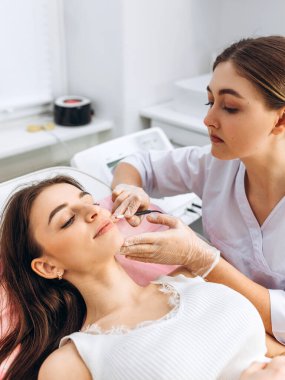 Dermatologların ellerinin elektro epilasyon yaparken yakın plan görüntüsü. Yüzdeki elektroliz süreci. Güzellik konsepti, elektroliz iğnesi. Kozmetik tıp dolabında çalışan bir doktor..