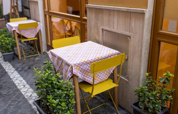 Lege tafels en gele stoelen door een trattoria in Rome, Italië. Gezellige oude straat, Buitenshuis eten concept, reizen — Stockfoto