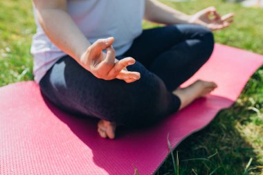 Lotus duruşu yakın. Yaz parkında yoga egzersizi yapan bir kadın. Çim ya da spor konsepti üzerine yoga