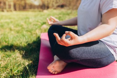 Lotus duruşu yakın. Yaz parkında yoga egzersizi yapan bir kadın. Çim ya da spor konsepti üzerine yoga