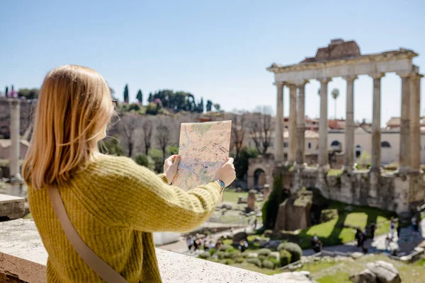Счастливая туристка стоит возле Римского форума, старых руин в центре Рима, Италия. Концепция путешествия знаменитых достопримечательностей. Девушка с картой идет в солнечный день, без лица — стоковое фото