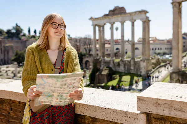 Roma Forumu 'nun yanında mutlu bir sarışın kadın turist duruyor. Roma, İtalya' nın merkezinde eski kalıntılar. Seyahat eden ünlü simgeler kavramı. Haritalı kız güneşli bir günde yürüyor — Stok fotoğraf