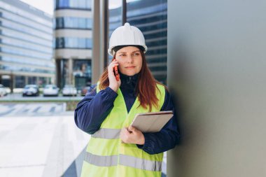 Hüsrana uğramış genç mimar kadın telefonda konuşuyor. Kötü haberler var. İnşaatçı beyaz kask ve güvenlik yeleği giyiyor..