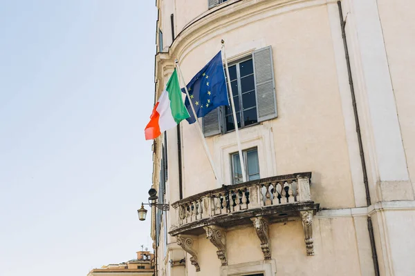 Flag of Italy with EU flag hanging on the balcony of a house