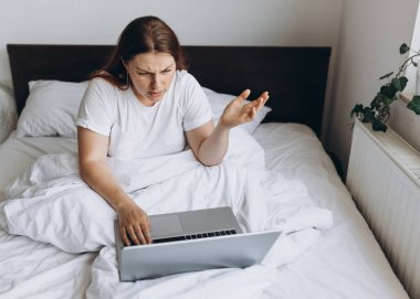 Tembel bir günde dizüstü bilgisayarı olan stresli genç bir kızıl kadın. Çevrimiçi eğitim, çalışma ya da alışveriş. Alternatif ofis ve serbest çalışma için teknoloji kadını kavramı