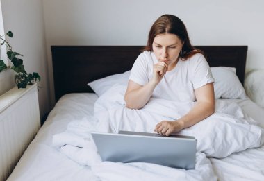 Tembel bir günde dizüstü bilgisayarı olan stresli genç bir kızıl kadın. Çevrimiçi eğitim, çalışma ya da alışveriş. Alternatif ofis ve serbest çalışma için teknoloji kadını kavramı