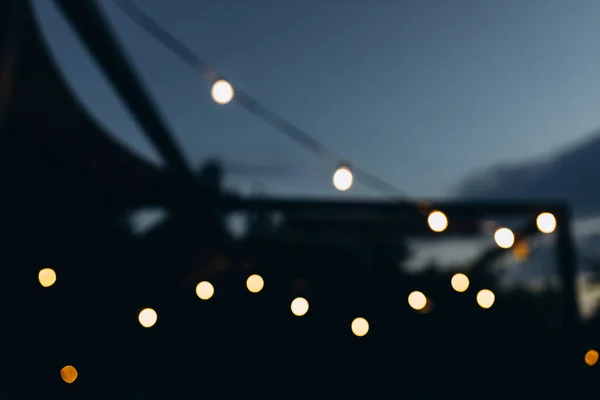 Decorative outdoor string lights at night time, Defocused Background, night city life backdrop, party time with bokeh balls