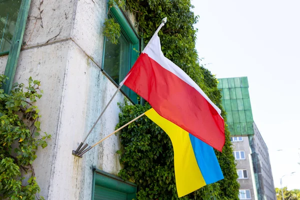 Flags of Poland and Ukraine on facade of a building waving in the wind. Symbol of national patriotism. Summer time