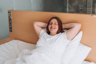 Portrait pretty young girl on bed in modern apartment in the morning. Enjoying the morning, beautiful woman resting in the room