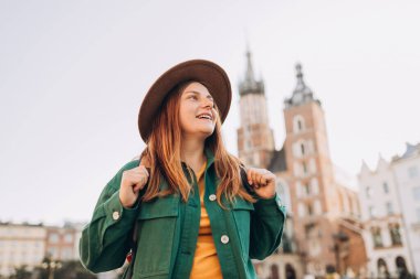 Güneş ışığında ünlü bir katedral, Krakow 'daki Pazar Meydanı' nda turist bir kadın, sonbaharda Avrupa 'yı geziyor. Aziz Mary Bazilikası