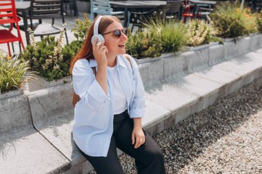 Şehir arka planında, kablosuz kulaklıklardan müzik dinleyen mutlu bir genç kızın portresini yakın plan çek. Müzik aşığı müziğin tadını çıkarıyor. Yaşam tarzı kavramı.