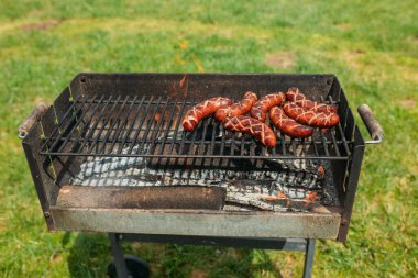 Izgara ızgarada domuz sosisi. Sosisler ızgarada, duman ve alevler arka planda