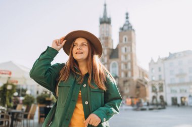 Güneş ışığında ünlü bir katedral, Krakow 'daki Pazar Meydanı' nda turist bir kadın, sonbaharda Avrupa 'yı geziyor. Aziz Mary Bazilikası