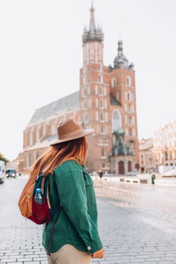 Güneş ışığında ünlü bir katedral, Krakow 'daki Pazar Meydanı' nda turist bir kadın, sonbaharda Avrupa 'yı geziyor. Aziz Mary Bazilikası