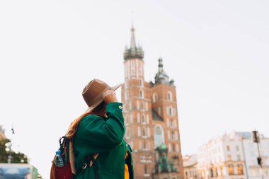 Güneş ışığında ünlü bir katedral, Krakow 'daki Pazar Meydanı' nda turist bir kadın, sonbaharda Avrupa 'yı geziyor. Aziz Mary Bazilikası
