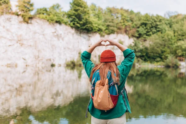 Happy Woman hiking in woods. Adventure women enjoying view of majestic mountain lake explore travel. Freedom and active lifestyle concept. Girl making by hands in shape of love heart.