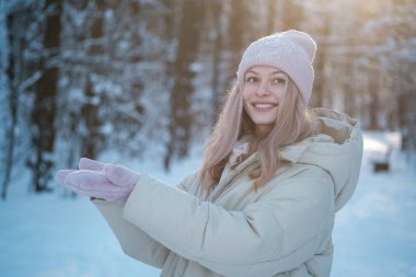 beautiful young woman looks at the palms in mittens in a beautiful winter park. blank for advertising