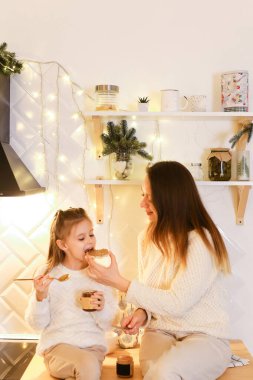 Anne ve kızı kahvaltı hazırlıyor. Ekmeğe badem ya da fıstık ezmesi sürüyorlar..