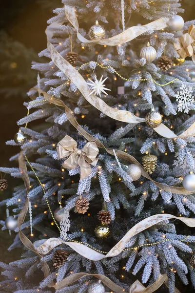 Blauw versierde kerstboom met decoratieve ballen en bloemenslingers, zonlicht. — Stockfoto