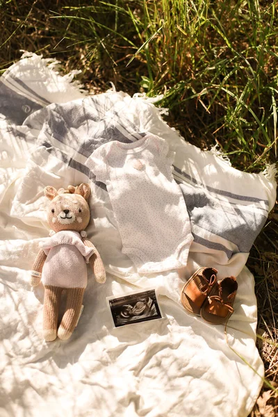 Wenig handgemachte Babykleidung. Ultraschallbild. Neugeborene Kleidung auf beigem Hintergrund mit Gras — Stockfoto