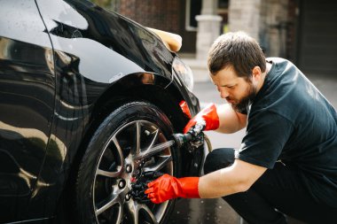 Kakuasyalı Amerikan sakallı adam araba tekerleklerini suyla yıkıyor ve evin önünde jet sürüyor..