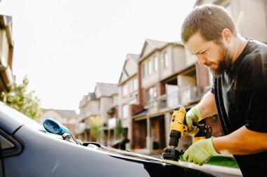 Amerikalı bir adam evin önünde araba cilalıyor ve parlıyor..