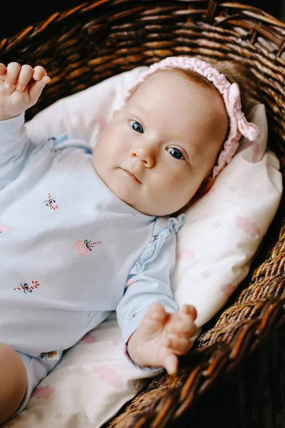 Schattige kleine blauwe ogen baby liggend in rieten mand op de vloer. — Stockfoto