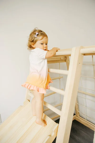 Baby girl play with developmental wooden structure at home or kindergarten or daycare center — Stock Photo, Image