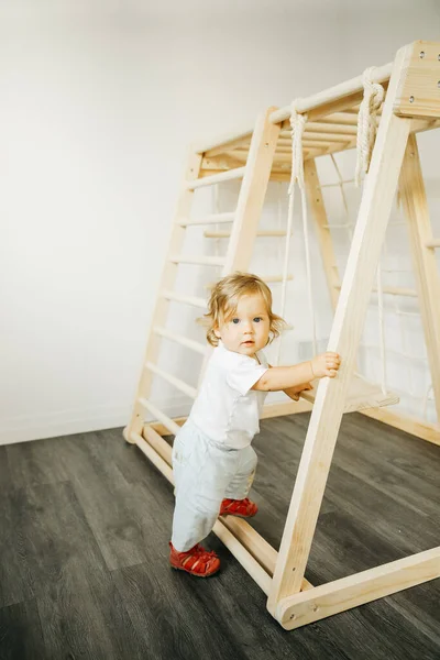 Дитяча дівчинка грає з дерев'яною структурою розвитку вдома або в дитячому садку або в центрі догляду за дітьми Стокове Зображення
