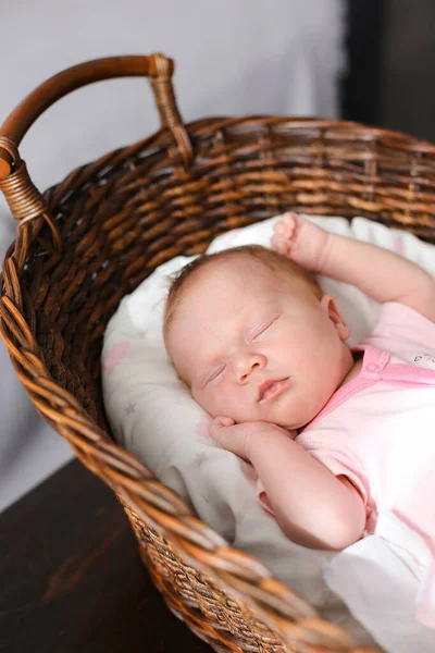 Close up caucasiano bebê menina dormindo em cesta de vime no estúdio. — Fotografia de Stock
