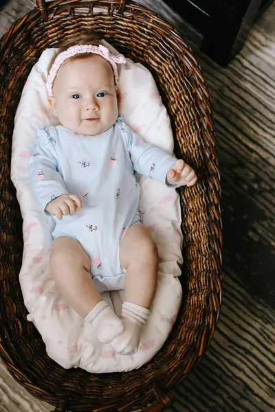 上の写真かわいい赤ちゃんが床の上にウィッカーバスケットに横たわっています. — ストック写真