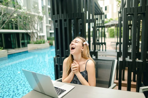 Молода красива дівчина дуже щаслива з ноутбуком біля басейну на суні Стокове Фото