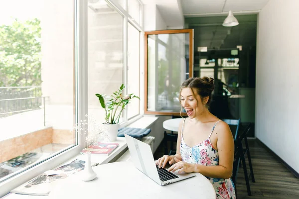 Молода щаслива дівчина сидить в кафе і серфінг Інтернет за ноутбуком . Стокове Фото