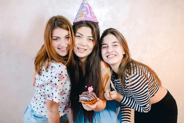 Adoráveis meninas amigáveis celebrar aniversário de suas amigas e se divertir de pé no fundo da parede de luz no quarto. — Fotografia de Stock