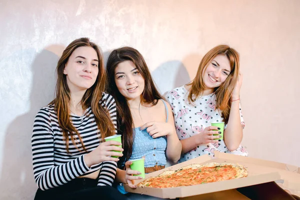 Ragazze carine fresco trascorrere del tempo e gustare la pizza, sedersi sul pavimento in camera da letto luminosa in serata . — Foto Stock