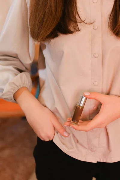 Elegantní smyslná mladá žena držící parfém, zlaté tóny — Stock fotografie