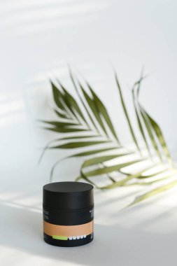 Beyaz arka planda yeşil yapraklı plastik güzellik şişesi.